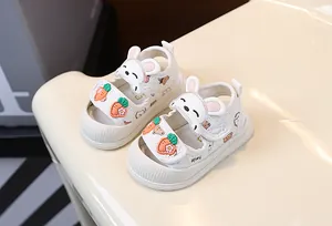 Détail de sandales blanches pour bébé avec de jolis lapins et carottes sur les scratchs.