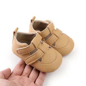 Weiche hellbraune Baby-Lauflern-Sandalen aus Kunstleder für Neugeborene in der Hand