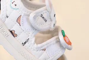 Vue rapprochée de sandale blanche pour bébé avec velcro lapin et carotte mignon.