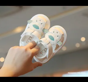 Close-up view of white infant closed-toe sandals with a cute cartoon sheep motif