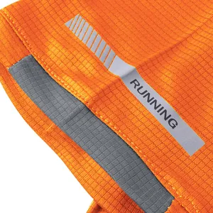 Macro detail of orange quick-dry running shirt showing mesh fabric and reflective strip.