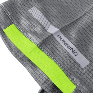 Close-up of grey quick-dry running shirt with reflective RUNNING strip and green detail.