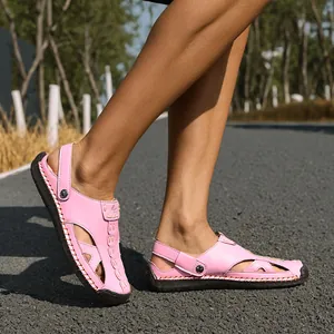 Close-up of pink hollowed-out leather sandals on asphalt road for summer outdoor leisure