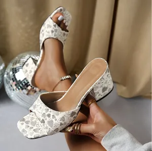 Detailed macro view of white square toe sandals with grey heart print and chunky heels