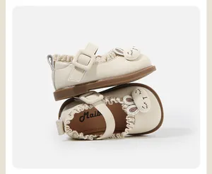 Close-up of beige baby girl Mary Jane shoes with cute bunny ear design and ruffles