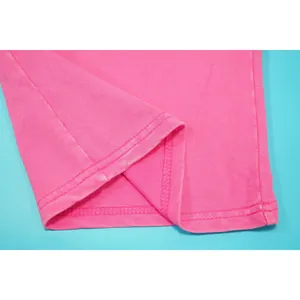 Close-up van roze gewassen katoenen stof met hoogwaardige stiksels en textuur detail.