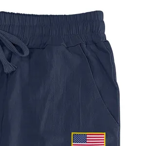 Détail de la taille du pantalon en lin avec cordon de serrage et écusson drapeau USA.