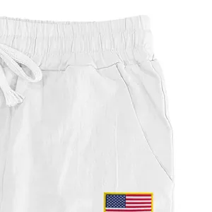 Gros plan d'un pantalon en lin blanc pour homme avec écusson drapeau américain.