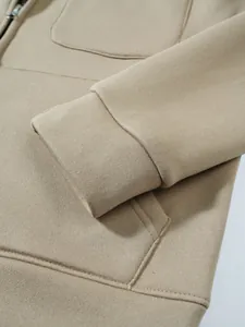 Makroaufnahme der gerippten Manschette und Tasche eines beigen Herren-Kapuzenpullovers.