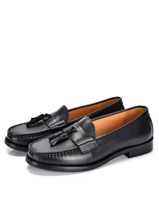 Classici mocassini da uomo in pelle nera con nappe su sfondo bianco per look elegante