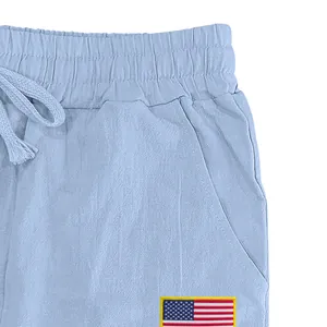 Détail gros plan de la taille et de l'écusson drapeau US sur un pantalon en lin bleu