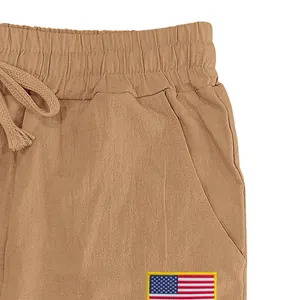 Gros plan d'un pantalon en lin kaki avec taille élastique et écusson du drapeau américain