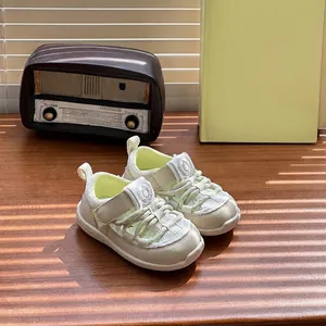 Detail shot of cream baby sandals with breathable mesh and sturdy Velcro straps on a wooden surface
