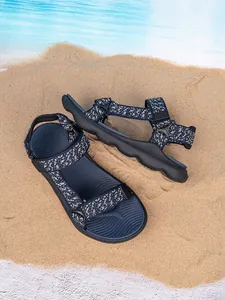 Detail view of blue patterned boys outdoor beach sandals placed on natural sand texture