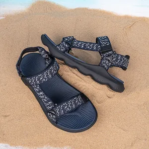Macro detail view of boys' outdoor sandals featuring patterned straps on natural beach sand