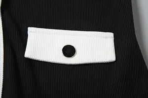 Makro-Detail der schwarz-weißen kontrastierenden Rippstricktasche mit schwarzem Knopf