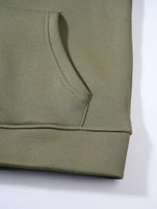 Detailaufnahme der Tasche und des gerippten Saums eines olivgrünen Kapuzenpullovers