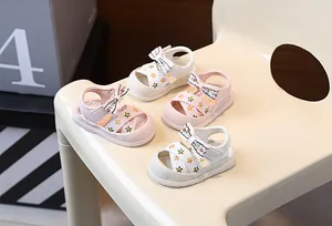 Détail de sandales pour bébés filles avec broderies florales et nœuds en rose et blanc