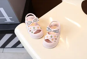 Vue détaillée des sandales roses pour bébés avec broderie florale et petit nœud.