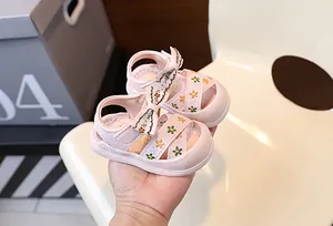 Gros plan de sandales roses pour fillettes avec broderies florales et nœud à la main