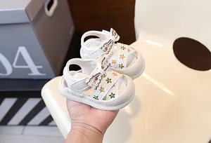 Gros plan de sandales blanches pour bébé avec broderie florale colorée et nœud mignon
