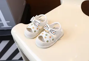 Vue détaillée des sandales blanches pour bébés filles avec broderie florale et nœud