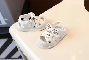 Gros plan sur de jolies sandales blanches pour bébés filles avec broderie florale et nœud