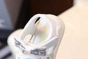 Vue macro détaillée de sandales blanches pour fillettes avec broderies et nœud papillon