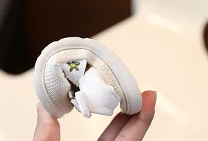 Gros plan d'une sandale blanche souple pour bébé avec broderie florale et semelle tendre