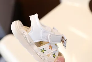 Vue détaillée de sandales blanches pour bébé avec broderies florales et velcro