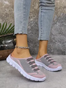Detailed close-up of pink knit breathable slip-on mules worn with denim jeans outdoors