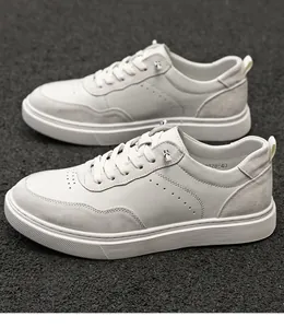 Top-down view of men's white suede low-top casual sneakers on asphalt background