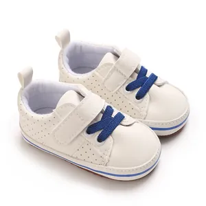 Close-up of white newborn baby boy walking shoes featuring blue laces and a soft sole.