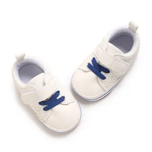 Detail view of white baby walking shoes with blue laces and adjustable Velcro strap.