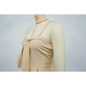 Close-up view of a beige strapless jumpsuit featuring an elegant tie-front knot design