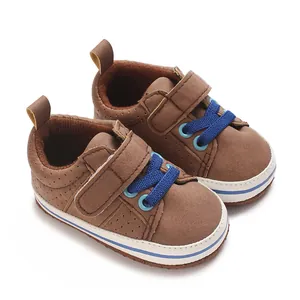 Close-up of brown newborn baby boy walking shoes with blue laces and Velcro strap