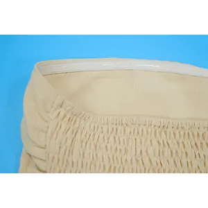 Detail macro view of the silicone anti-slip strip and smocking on a beige tube jumpsuit