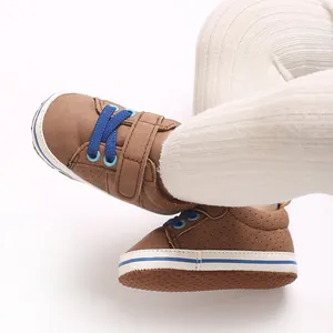 Close-up view of brown suede baby walking shoes with blue laces and soft white soles.