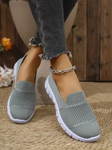 Nahaufnahme von atmungsaktiven grauen Mesh-Slippern für Damen mit fester weißer Sohle
