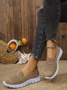 Detailansicht der khakifarbenen Mesh-Loafer mit grauen Jeans auf einer gewebten Matte
