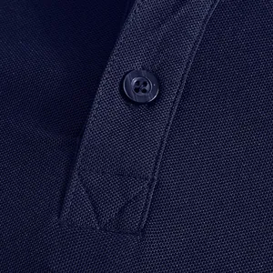 Detailed macro shot of the breathable piqué fabric and button on a navy blue polo shirt