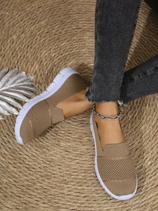 Detailaufnahme von khakifarbenen, atmungsaktiven Mesh-Slippern auf einer gewebten Strohmatte