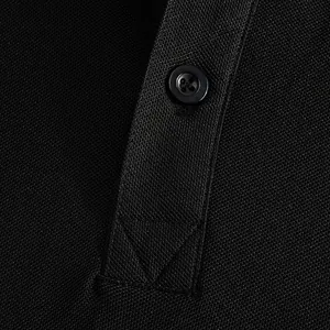 Close-up of breathable piqué fabric and button detail on black polo shirt