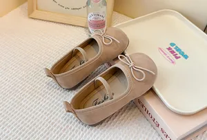Close-up view of beige children's Mary Jane shoes with delicate bow and elastic strap
