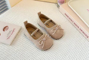 Beige suede Mary Jane shoes with bow detail on textured background