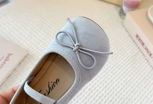 Detailed close-up of light blue suede children's Mary Jane shoes with bow decoration
