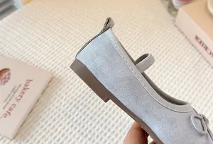 Close-up of light blue suede Mary Jane shoe with elastic strap and bow detail