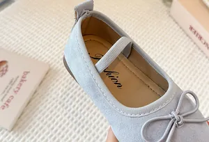 Close-up detail of light blue children's Mary Jane shoe with a bow and elastic strap