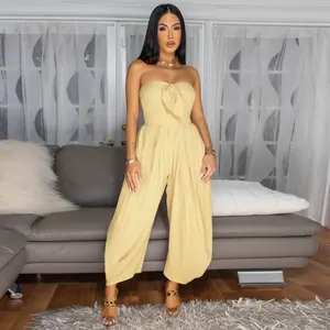 Full-body shot of a chic yellow strapless jumpsuit worn by a model in a cozy living room