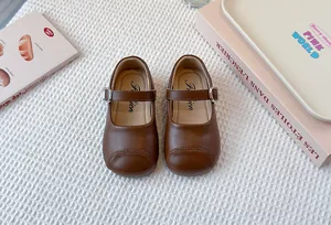 Top view of brown children's Mary Jane leather shoes featuring silver buckle straps.